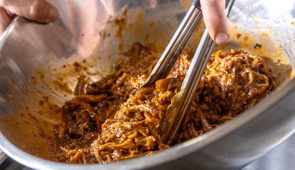 Crossbuck BBQs Pulled Pork Being Tossed in its Black Molasses Sauce