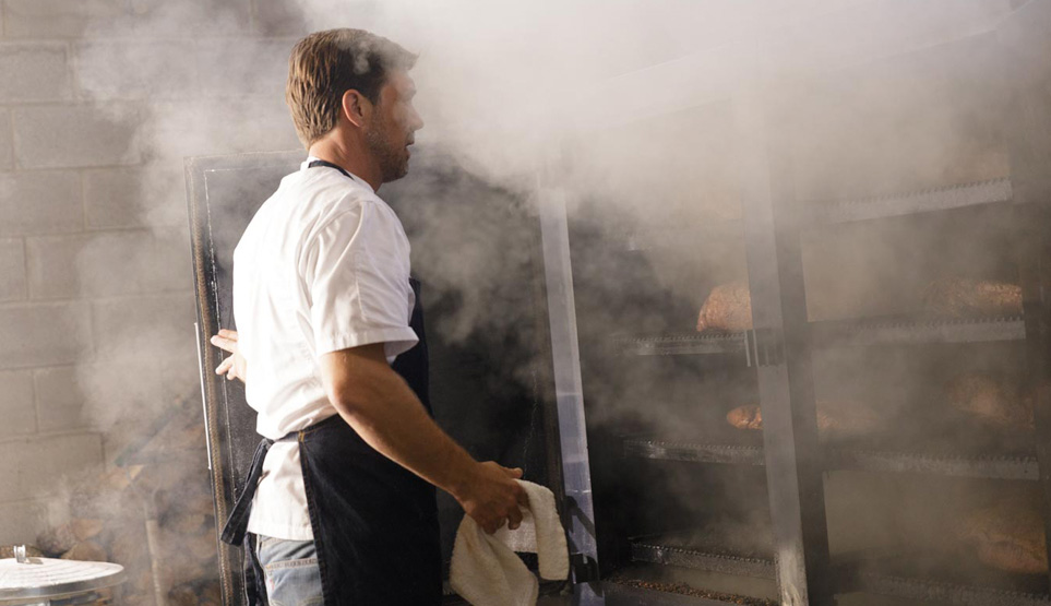 Pitmaster Tim McLaughlin pulling pork butts out of the smoker